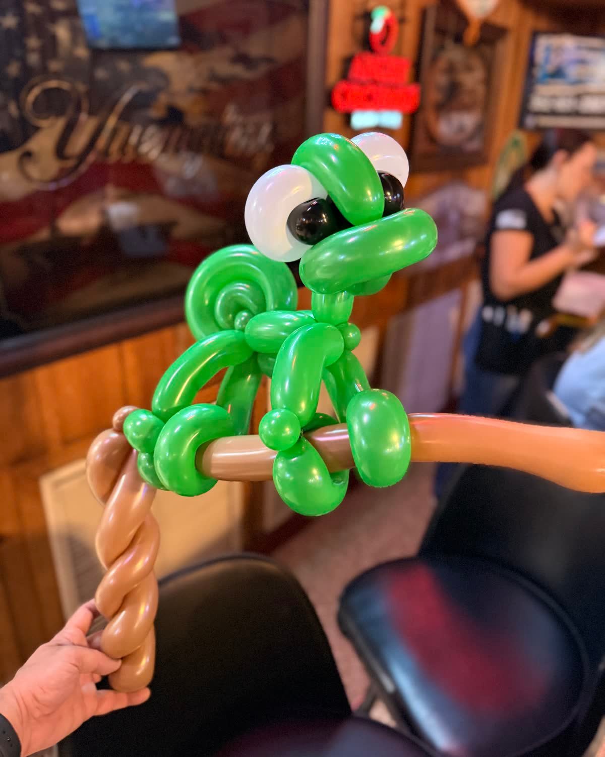 Green frog balloon sculpture at an event.